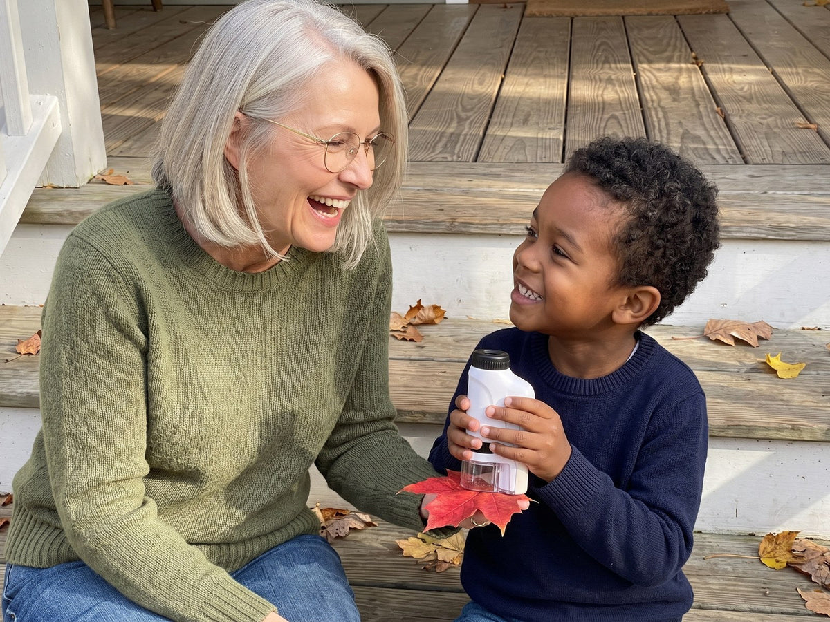A grandmother laughs with her grandson on the porch steps. He has his Miniscope and a red leaf.