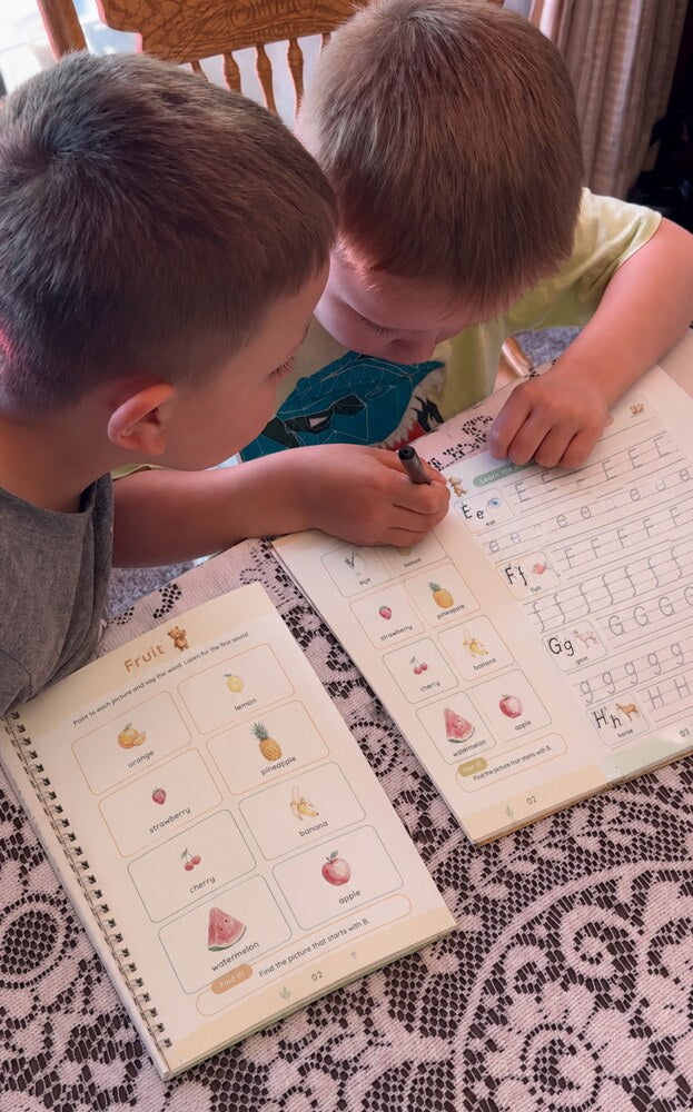 Two boys trace letters side by side in their copybooks