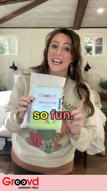 A woman shows the Groovd Math copybook to the camera, caption: so fun