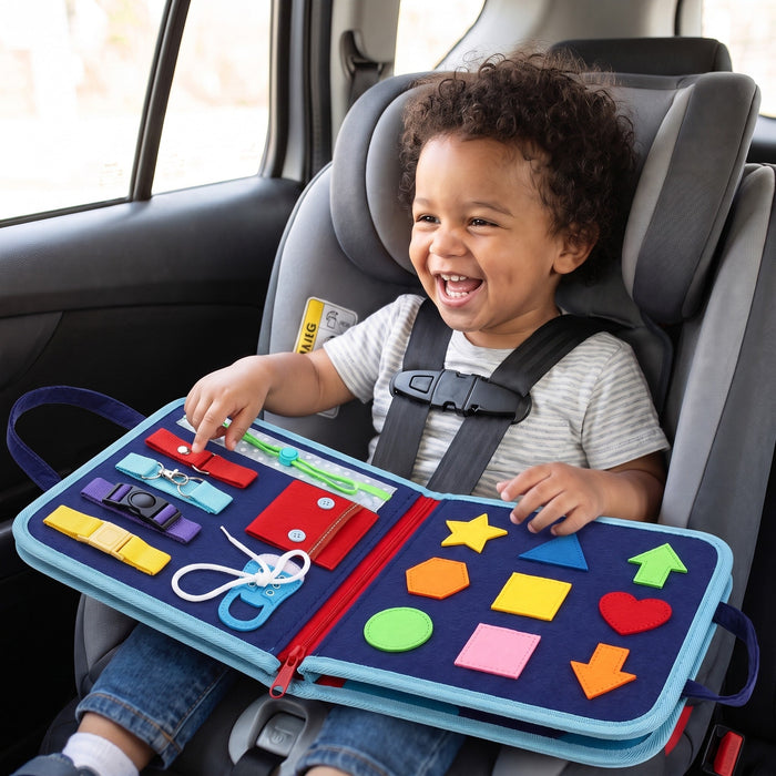 A laughing toddler in a car seat with the open board across their lap, showing straps, a shoelace and felt shapes
