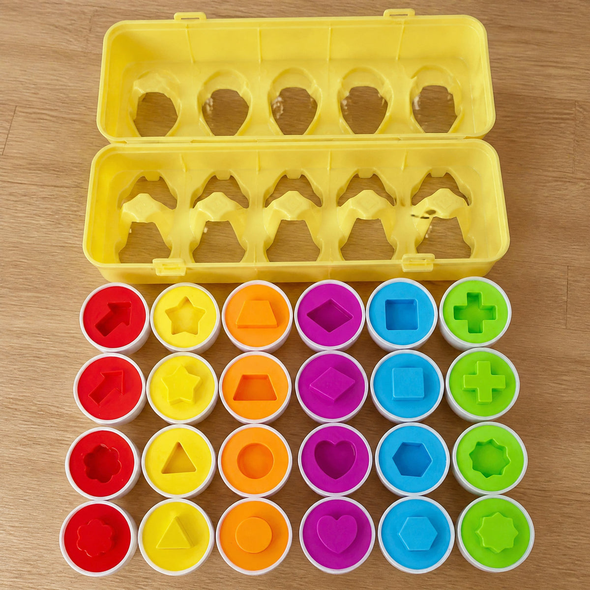 All 24 egg halves in matching pairs, in six colors with shapes like a star, heart, cross and hexagon, below the empty carton
