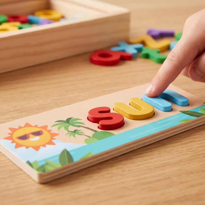 Close-up of a child's finger pressing a blue n into the sun card, next to a red s and a yellow u already in place