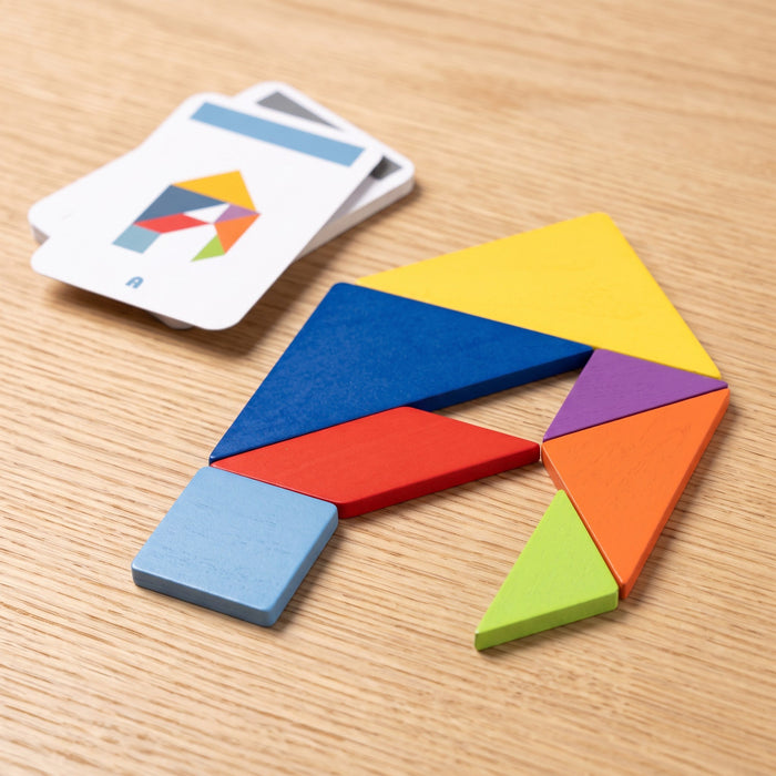 The seven wooden pieces arranged into the letter A on a table, next to the matching letter A pattern card